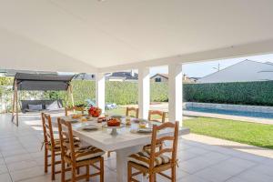 une table blanche et des chaises sur une terrasse dans l'établissement Ma-la Beach House by HostWise, à Marinhas