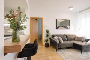 - un salon avec un canapé et un vase de fleurs dans l'établissement Apartma Masada, à Maribor