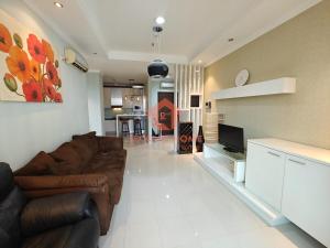a living room with a brown couch and a tv at Strategic 1BR Bellezza Apt Green Gem Max 6 in Jakarta