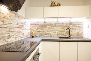 - une cuisine avec des placards blancs et un mur en pierre dans l'établissement Apartma Masada, à Maribor