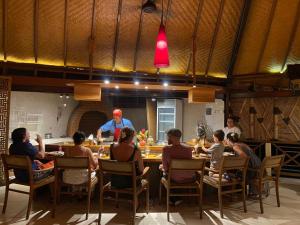 a group of people sitting at a table in a restaurant at Puri Dajuma Beach Eco-Resort & Spa in Pulukan