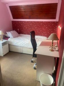 ein Schlafzimmer mit einem Bett und einem Schreibtisch mit einer Lampe in der Unterkunft Firs Drive in Cranford