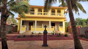 a yellow house with palm trees in front of it at Ferns Cottage in Calangute