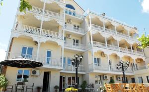 un gran edificio blanco con una sombrilla delante en Hotel Old Marani, en Itʼkhvisi