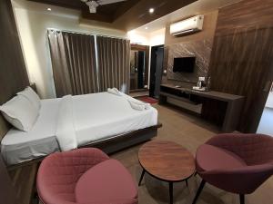 a hotel room with a bed and two chairs and a desk at Kusum Resort in Badami