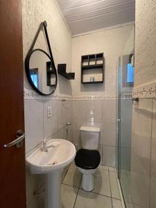 een badkamer met een wastafel, een toilet en een spiegel bij casa celeste in Imbituba