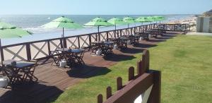 eine Reihe von Tischen mit grünen Sonnenschirmen am Strand in der Unterkunft Casa Mari Suites in Aracati