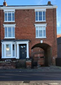 a red brick house with a black door and an archway at Luxury Apartment in Shropshire sleeps 4 in Shrewsbury