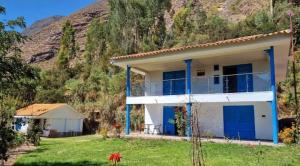 HuayllabambaRelaxing small cottage in nature的山前有一栋白房子，蓝色的门。