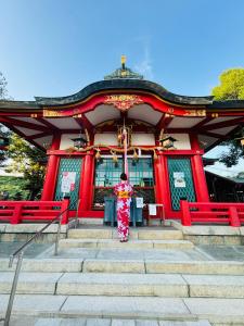 a woman in a kimono standing in front of a building at 藤花楼akagawa 登録文化財 in Osaka