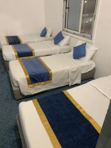 الشقق الأولى السكنية في المدينة المنورة: ثلاثة أسرة في غرفة مع بطانيات زرقاء وصفراء