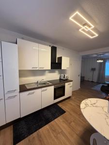 a kitchen with white cabinets and a sink and a table at Apartment Alana in Hannover