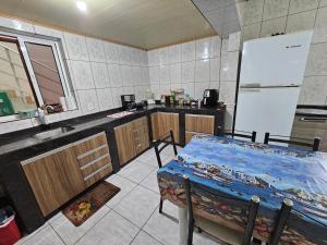 a kitchen with a table and a white refrigerator at Pousada Wisocki in Matinhos