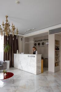 a woman standing behind a reception desk in a room at Mountain View Boutique Hotel in Almaty
