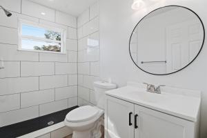 bagno bianco con servizi igienici e specchio di Elegant Auburndale Rooms Near the Speedway & Lake Myrtle ad Auburndale