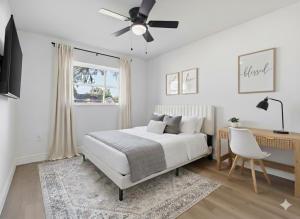 una camera da letto bianca con un letto e una scrivania di Elegant Auburndale Rooms Near the Speedway & Lake Myrtle ad Auburndale