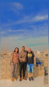 een groep van drie mensen die naast een bakstenen muur staan bij desert Pyramids view inn in Caïro