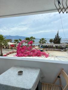 Una vista desde un balcón con una mesa y flores rosas. en Hotel Santa Paola, en Sarandë