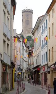 富瓦La Parenthèse à Foix的一条城市街道，两旁林立着建筑，远处可见一座城堡。