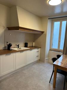 富瓦La Parenthèse à Foix的厨房配有白色橱柜、水槽和桌子
