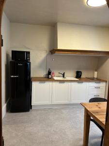 富瓦La Parenthèse à Foix的厨房配有黑冰箱和白色橱柜。 更多3张照片