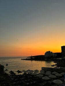Una puesta de sol en una playa con sombrillas en el agua en Hotel Santa Paola, en Sarandë 2 fotos más