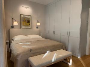 a white bedroom with a bed and a bench at Sanhaus Apartments - Apartament ROYAL - 3 minuty od plaży i deptaka in Sopot