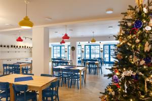 un árbol de Navidad en un restaurante con mesas y sillas en Hotel Edvard, en Frenštát pod Radhoštěm