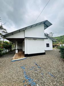 バガモンにあるPheonix home stayの砂利の庭に建つ黒い屋根の白い家