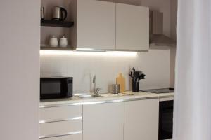 a white kitchen with a sink and a microwave at My Fiorella Apartment in Terni