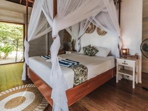 AmpanaReconnect - Private Island Resort & Dive Center Togean - Buka Buka Island的一间卧室，里面有一张带帷幔的床
