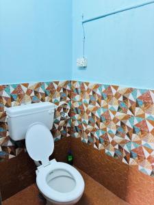 a bathroom with a toilet and a mosaic wall at Pheonix home stay in Vagamon +13 photos