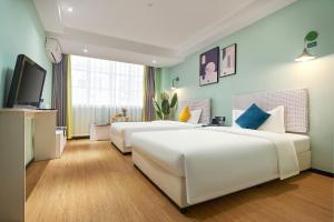 una camera da letto con due letti e una TV a schermo piatto di LIU YUAN Amoy Smart Hotel 厦门留苑智能酒店 a Xiamen