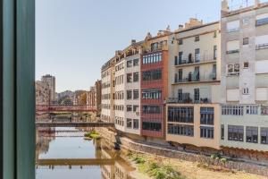un grupo de edificios junto a un río en Flateli Ballesteries, en Girona