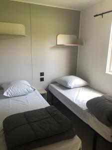 een kamer met twee bedden en een raam bij Mobilehome riviera avec terrasse 23 in Saint-Gervais