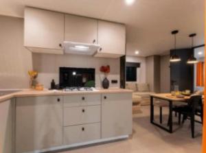 een keuken met witte kasten en een eetkamer bij Mobilehome riviera avec terrasse 23 in Saint-Gervais