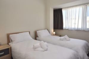 due letti in una camera d'albergo con lenzuola bianche di Bright and Central 2 Bedroom with Harbour view a Msida