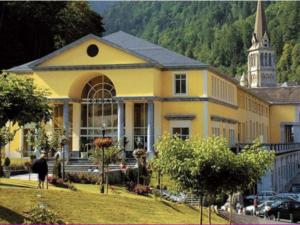 ein großes gelbes Gebäude mit einer Kirche im Hintergrund in der Unterkunft Chalet Mitoyen 3 Chambres, Terrasse, Proche Centre Cauterets, Navette Ski Gratuite - FR-1-401-254 in Cauterets
