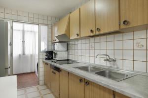a kitchen with wooden cabinets and a stainless steel sink at Casa En El Centro De Barbate in Barbate