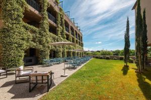 ein Innenhof eines Gebäudes mit Stühlen und Sonnenschirmen in der Unterkunft SOWELL HOTELS Les Chevaliers in Carcassonne