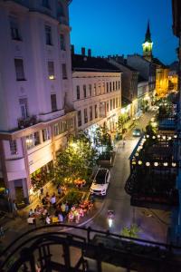 una calle de la ciudad por la noche con gente sentada en las mesas en Concept Apartments, en Budapest