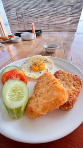a plate of food with a fried egg and vegetables at MenTari GuestHouse in Gili Gede