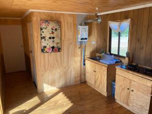 a kitchen with wooden walls and wooden floors and a window at Cabaña Vista Bosque in Catillo