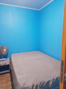 a bedroom with a blue wall and a bed at Dúplex em Tramandaí in Tramandaí