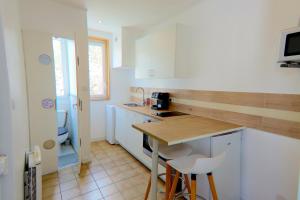 a kitchen with white cabinets and a table and chairs at Coin de paradis à Grenoble in Poisat