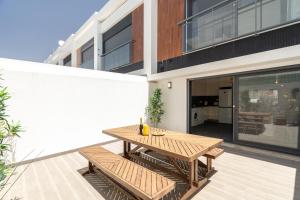a patio with a wooden table and benches in front of a building at Spacious house in Olhao in Quelfes