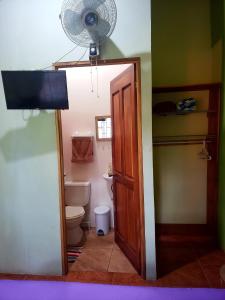a bathroom with a toilet and a fan at Arenal Hostel La Catarata in Fortuna