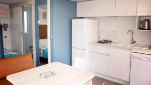 a kitchen with white cabinets and a sink and a table at ZEcamping 3 à 150m de la plage cadre unique de la presquîle de Giens in Hyères