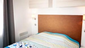 a bed with a wooden headboard in a bedroom at ZEcamping 3 à 150m de la plage cadre unique de la presquîle de Giens in Hyères