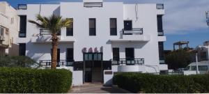 a white building with a palm tree in front of it at Cali Residence in Sharm El Sheikh +19 photos